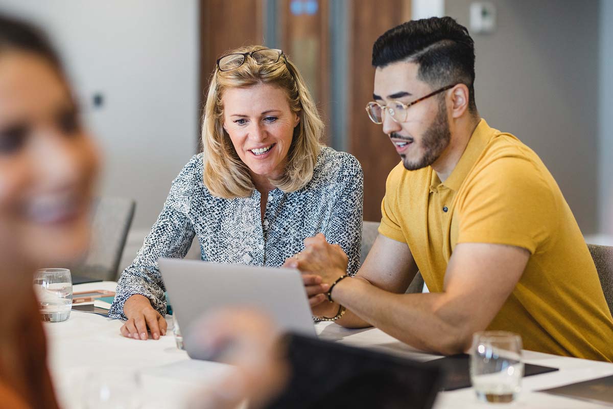 Colleagues discussing product data on laptop